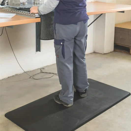 Tapis anti-fatigue professionnel en mousse placé devant un poste de travail pour réduire la fatigue liée à la station debout prolongée.