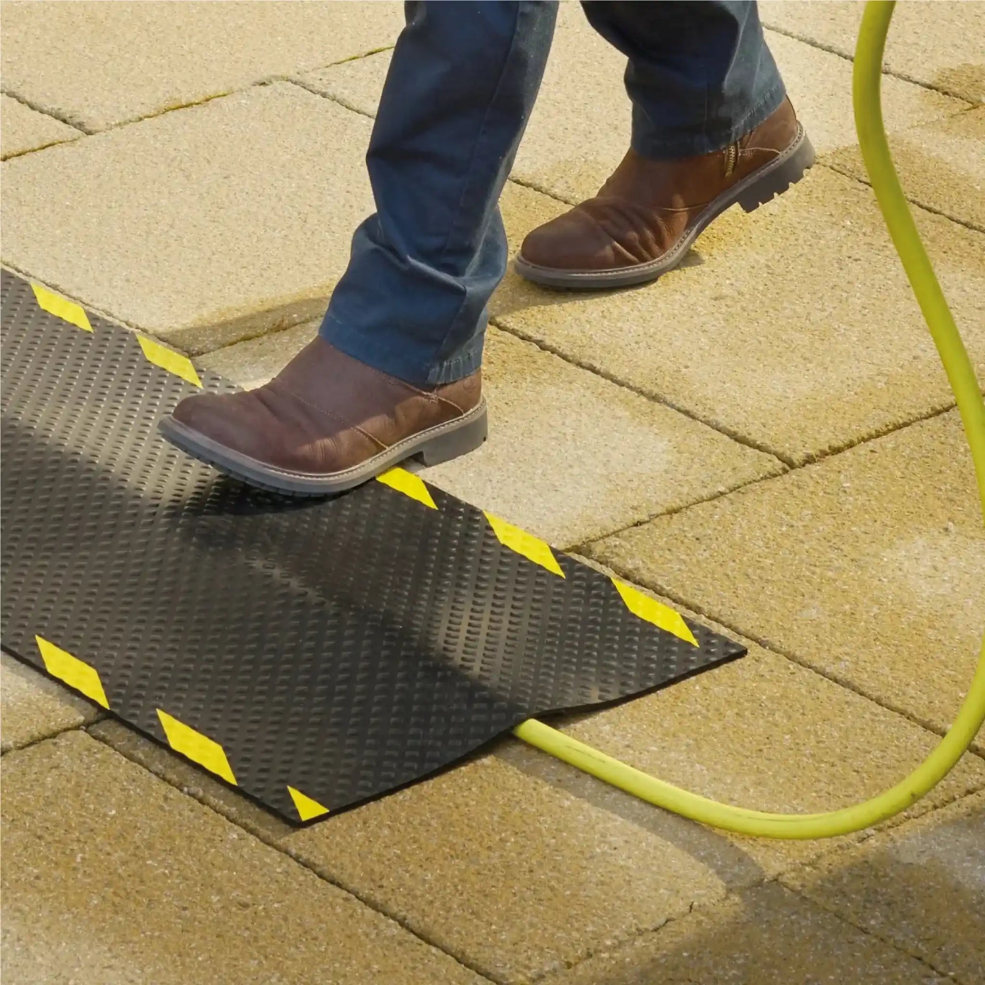 Gros plan sur un tapis passe-câble pour borne de recharge électrique protégeant efficacement le câble au sol contre l’usure et les chocs.