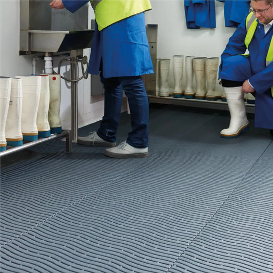Revêtement drainant antidérapant dans un vestiaire industriel permettant un drainage efficace et une meilleure sécurité au sol.