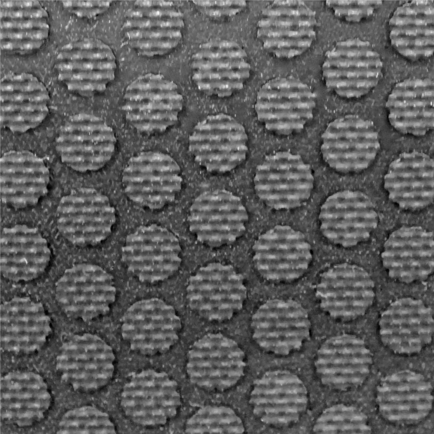 Gros plan de la surface en caoutchouc industriel à reliefs circulaires offrant une excellente adhérence et résistance au trafic intensif.