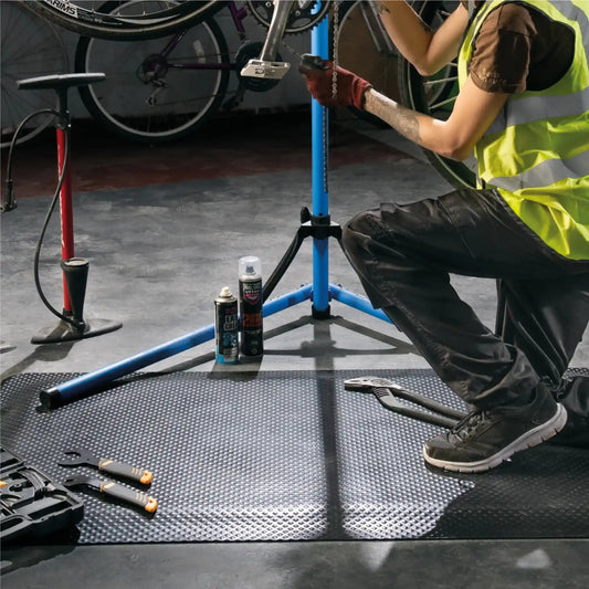 Tapis anti-fatigue professionnel pour atelier utilisé lors de la réparation d’un vélo afin d’améliorer le confort de travail.