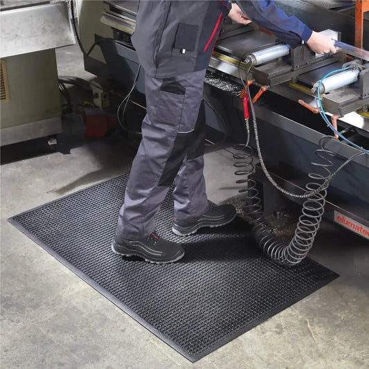 Tapis anti-fatigue professionnel industriel utilisé dans un atelier pour améliorer le confort et la sécurité des opérateurs.