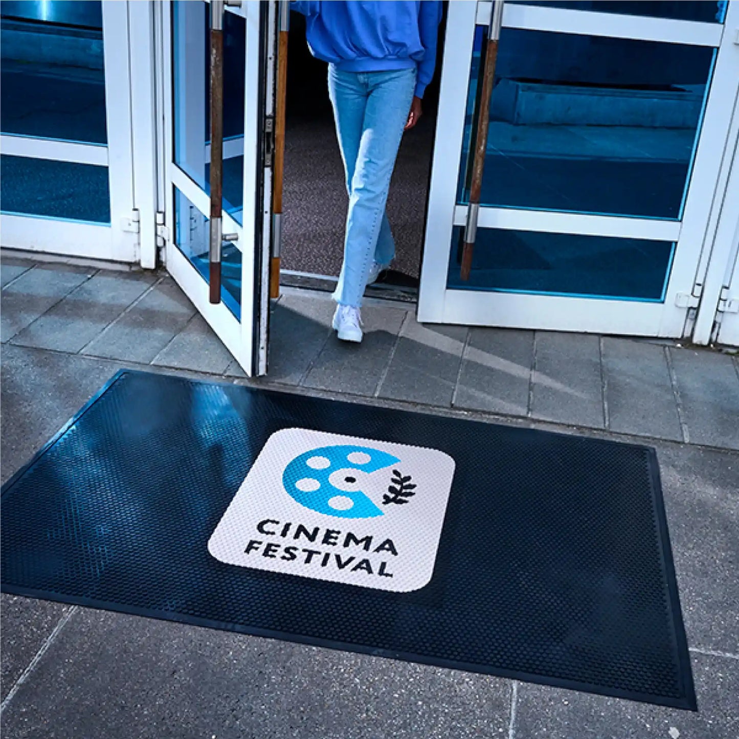 Tapis logo personnalisé en caoutchouc industriel installé devant une entrée pour retenir les saletés et sécuriser les accès.