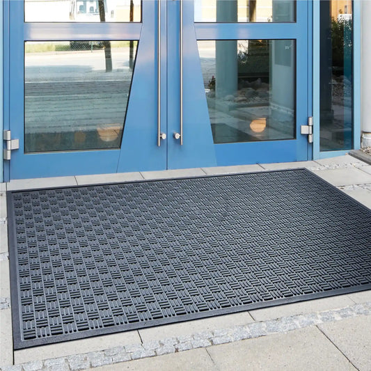 Tapis d’entrée professionnel en caoutchouc grattant installé devant une porte pour retenir les salissures et l’humidité.