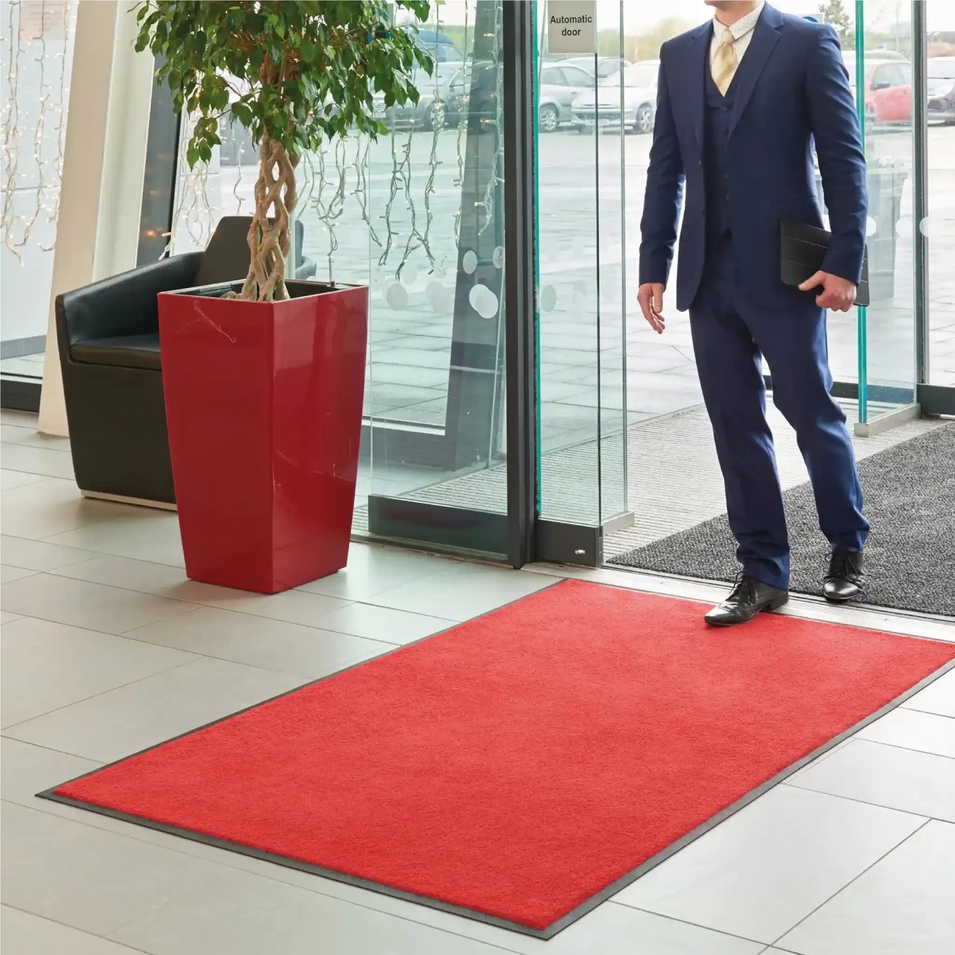 Tapis d’entrée professionnel couleur unie rouge installé dans le hall d’accueil d’une entreprise.