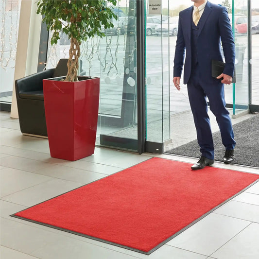 Tapis d’entrée professionnel couleur unie rouge installé dans le hall d’accueil d’une entreprise.