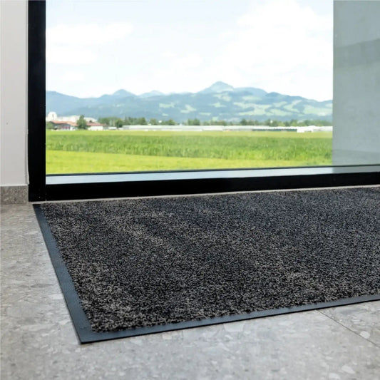 Tapis d’entrée professionnel écologique installé devant une baie vitrée pour retenir efficacement les salissures et l’humidité.