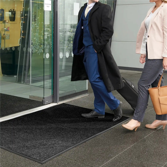Tapis d’entrée professionnel à rétention d’eau placé devant une entrée vitrée pour limiter l’humidité et les salissures.