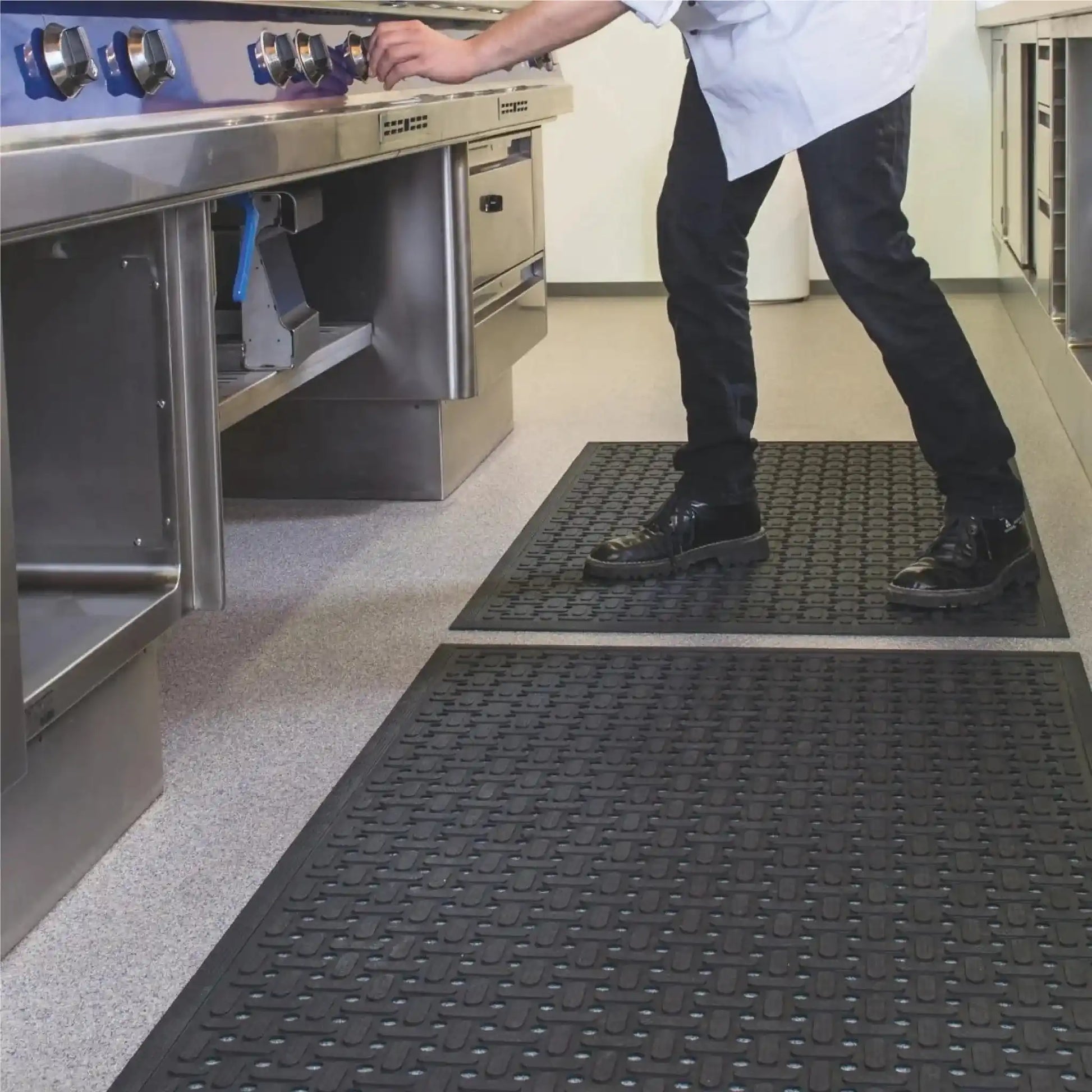 Tapis hygiénique drainant en caoutchouc utilisé dans une cuisine professionnelle pour améliorer le confort, l’adhérence et l’évacuation des liquides au poste de cuisson.