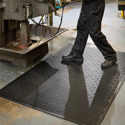 Tapis industriel en caoutchouc pour zones humides placé devant une machine-outil afin d’améliorer l’adhérence, le drainage et le confort des opérateurs.