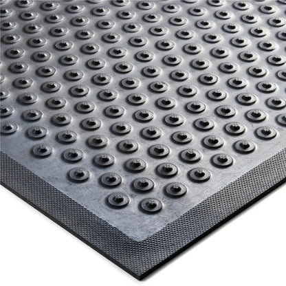 Gros plan sur la surface du tapis industriel grattant drainant de sécurité avec relief antidérapant favorisant l’évacuation des liquides et débris.