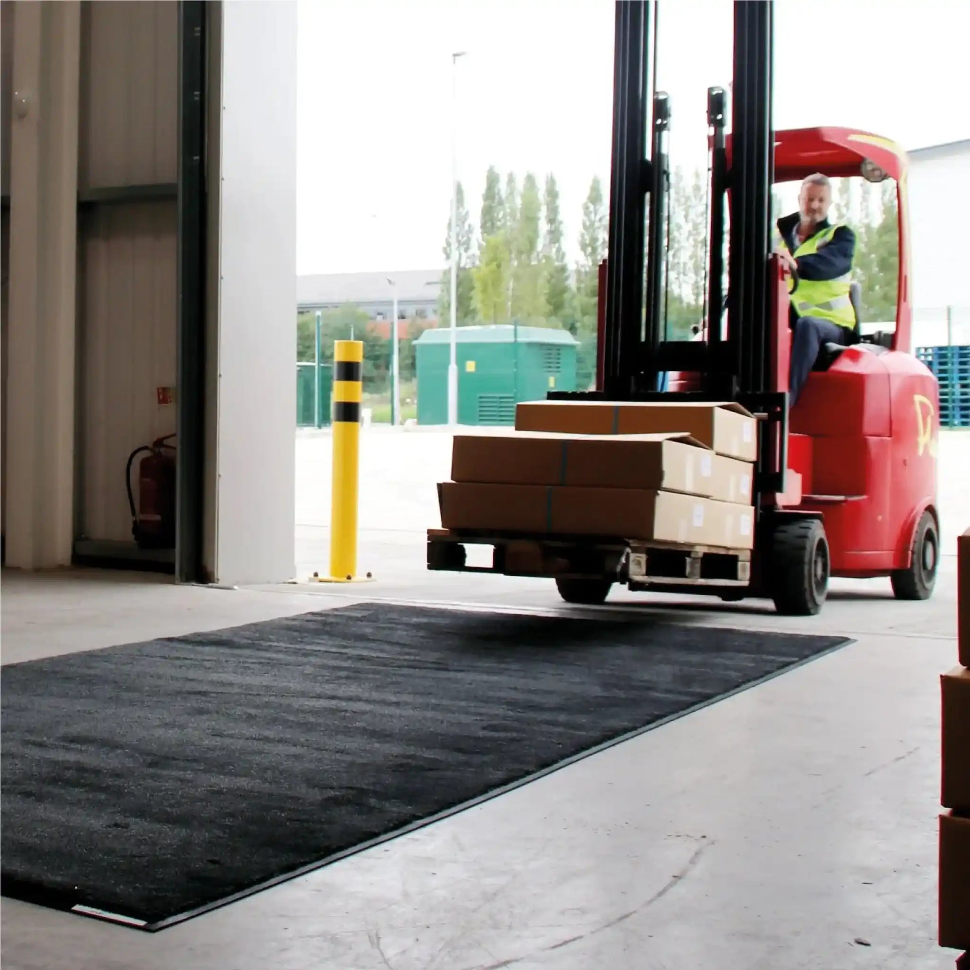 Chariot élévateur circulant sur un tapis industriel haute résistance pour zones de chargement et de manutention.