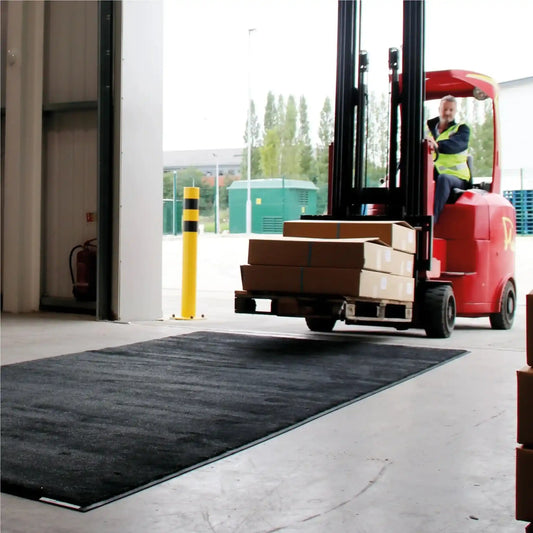 Chariot élévateur circulant sur un tapis industriel haute résistance pour zones de chargement et de manutention.