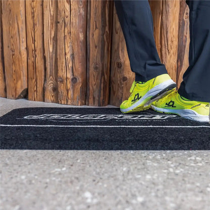 Employé debout sur un tapis logo personnalisé anti-fatigue conçu pour réduire la fatigue et améliorer l’ergonomie au travail.