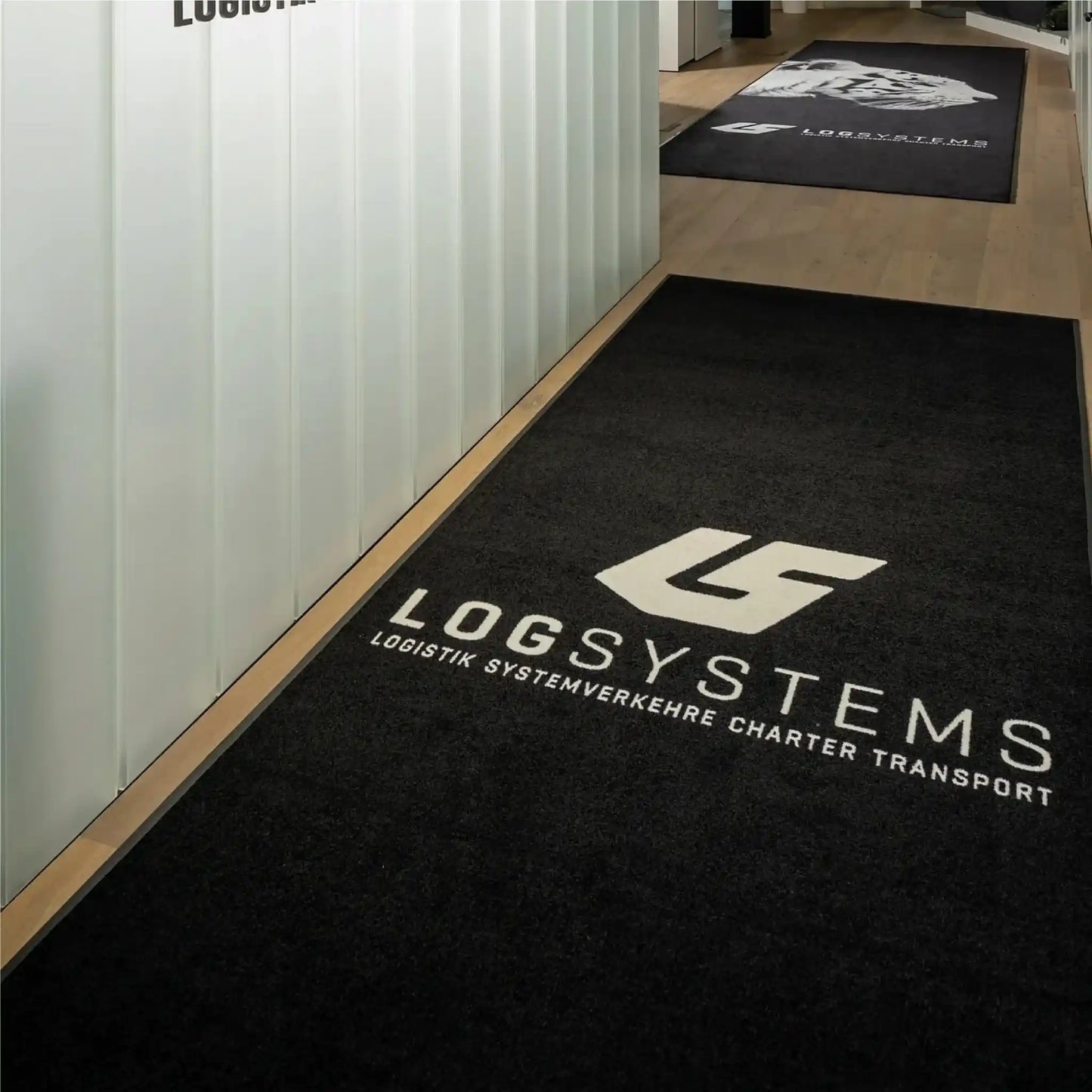 Tapis logo personnalisé grand format XXL installé dans un couloir d’entreprise pour guider les visiteurs tout en valorisant la marque.