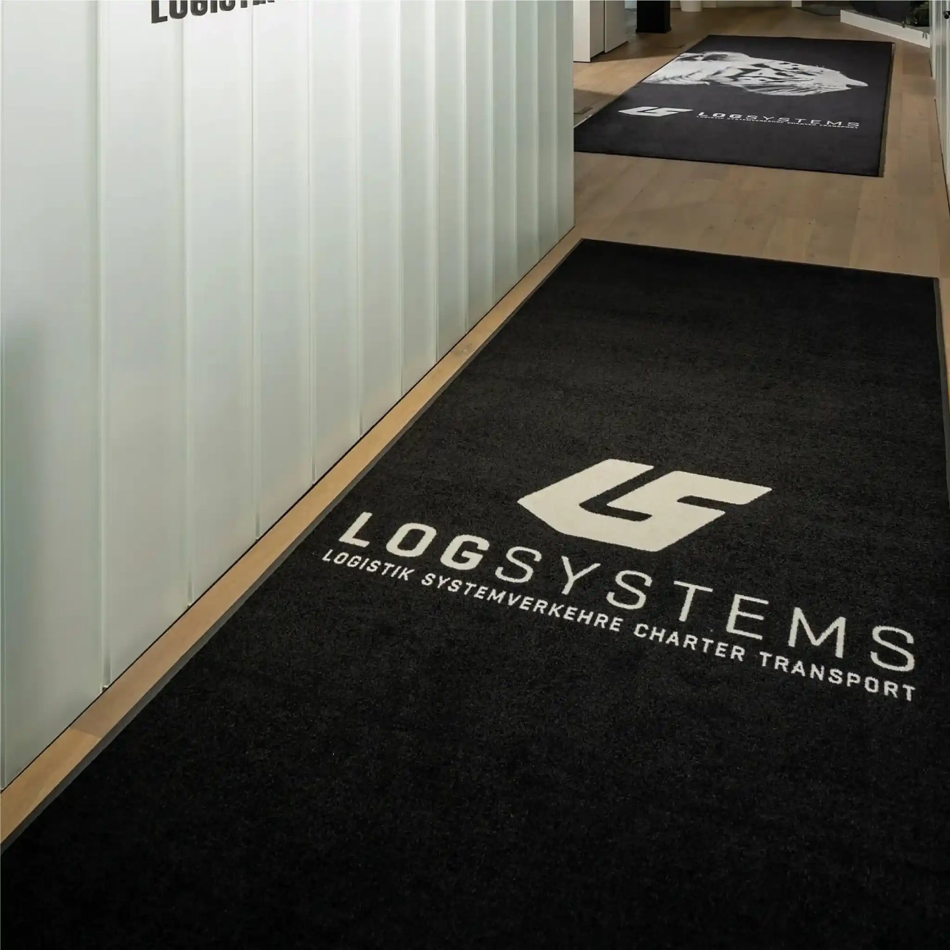 Tapis logo personnalisé grand format XXL installé dans un couloir d’entreprise pour guider les visiteurs tout en valorisant la marque.