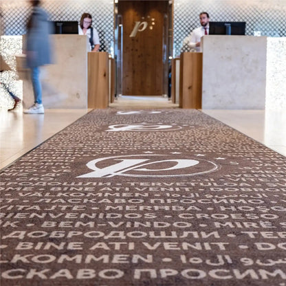 Tapis logo personnalisé grand format XXL placé dans le hall d’accueil d’un hôtel pour accueillir les visiteurs avec élégance.