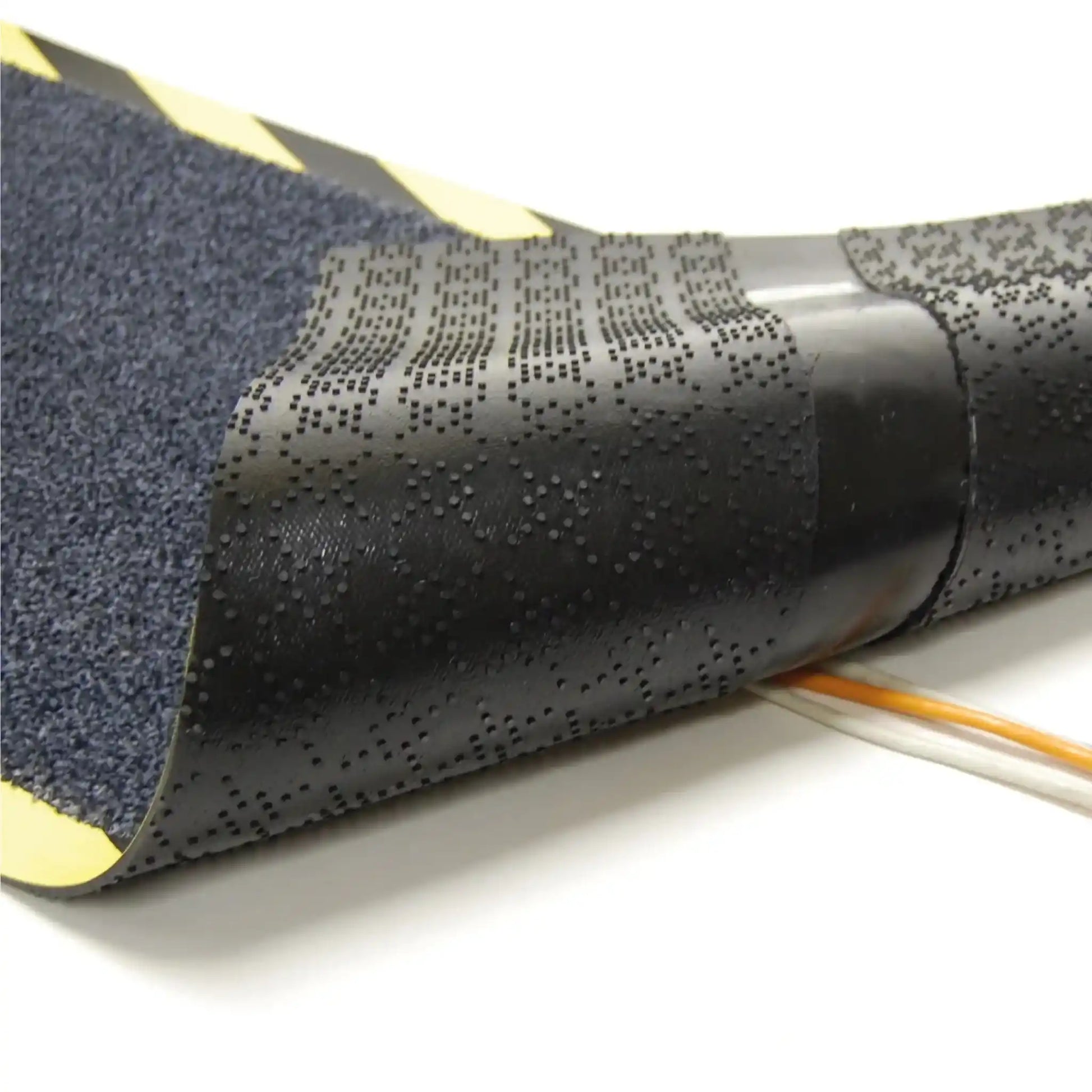 Vue détaillée du dessous du tapis passe-câbles professionnel montrant les rainures conçues pour accueillir et protéger les câbles électriques.