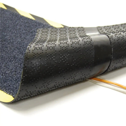 Vue détaillée du dessous du tapis passe-câbles professionnel montrant les rainures conçues pour accueillir et protéger les câbles électriques.
