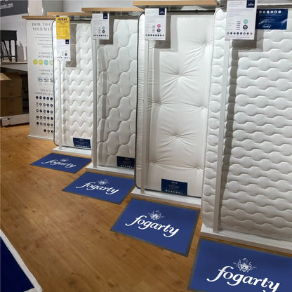 Tapis publicitaire personnalisé installé devant des produits en magasin pour mettre en avant l'identité visuelle de l'enseigne.